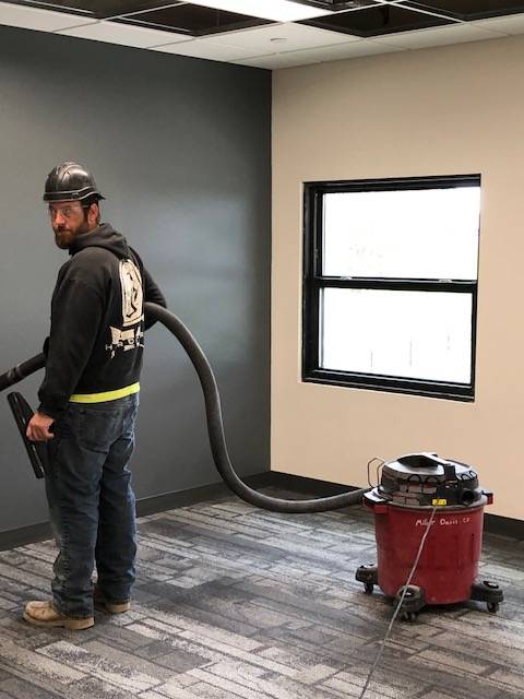 A construction worker vacuuming in a newly constructed room.